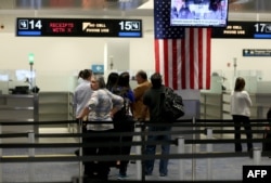 FILE - International travelers wait in line at a U.S. Customs and Border Protection checkpoint after arriving at Miami International Airport on March 4, 2015, in Miami, Florida. U.S. officials said on Saturday they would cease flagging travelers from certain countries targeted by the Trump executive order.