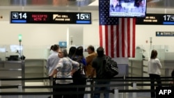 FILE - International travelers wait at a U.S. Customs and Border Protection checkpoint after arriving at Miami International Airport in Florida. Iran objects to a new U.S. law restricting visa-free travel rights for dual citizens and others.