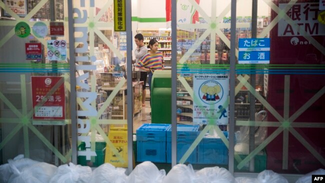 Taped up windows and bags filled with water to counter a flood surge greet last dash shoppers at a convenience store in the Shinagawa district of Tokyo on October 12, 2019, as the effects of Typhoon Hagibis begin to be felt in Japan's capital. (AFP)