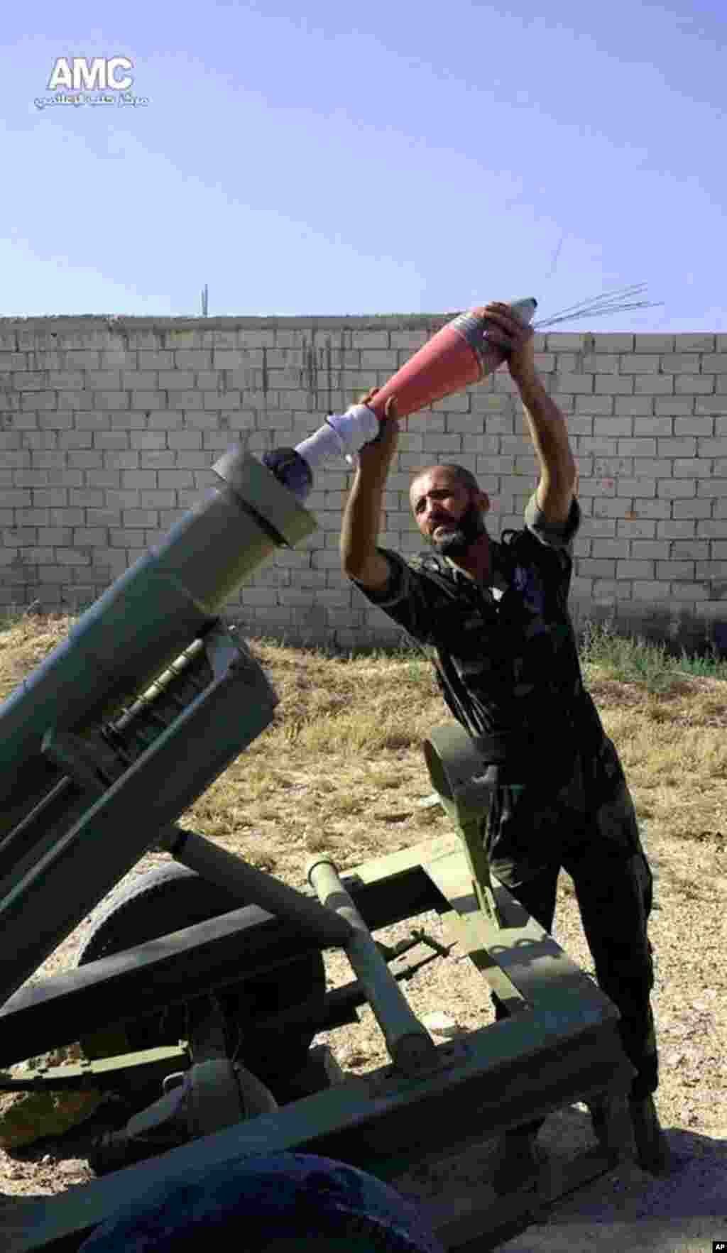 This citizen journalism image provided by Aleppo Media Center AMC shows a Free Syrian army fighter moments before firing a heavy mortar toward the airport in Aleppo, Syria, Sept. 2, 2013.