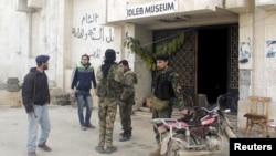 Rebel fighters stand outside Idlib museum in Idlib, Syria, after Islamist rebel fighters took control of the area, April 1, 2015. 