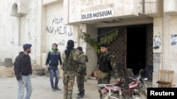 FILE - Rebel fighters stand outside Idlib museum in Idlib, Syria, after Islamist rebel fighters took control of the area, April 1, 2015. 