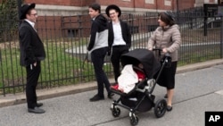 A woman, right, who identified herself as Ester, passes a group of boys, April 9, 2019, in the Williamsburg section of Brooklyn, New York. Ester says that she does not believe that the measles vaccination is safe.