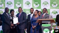 Kenyan electoral official Roselyn Akombe, center right, stands as President Uhuru Kenyatta, third from left, receives his electoral win certificate, later nullified, from Chairman of the Electoral Commission Wafula Chebukati, left, as Deputy President William Ruto, right, looks on at the results center in Nairobi, Kenya. Akombe resigned Wednesday, Oct. 18, 2017 in a statement from New York saying the rerun of the presidential election scheduled for Oct. 26 cannot be free and fair. 