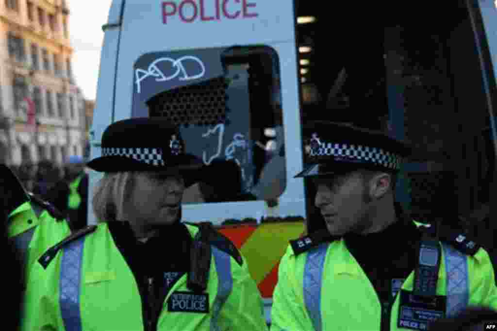 Police stand behind a vandalized police van as thousands of student protest against tuition fees at Whitehall in London, Wednesday, Nov. 24, 2010. Thousands of British students protested Wednesday against government plans to triple tuition fees, two weeks