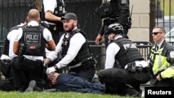 Police and rescue personnel tend to a man in Lafayette Park after the man lit his jacket on fire in front of the White House in Washington, April 12, 2019.