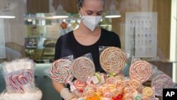 A sweets shop employee arranges candy canes, in Vienna, Austria, Nov. 23, 2021, as shops and restaurants are only allowed to offer take away and delivery services due to the COVID-19 lockdown.