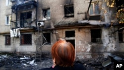 Seorang perempuan menangis di depan bangunan apartemennya yang hancur di kota Donetsk, Ukraina Timur (17/9).