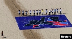 FILE - People from the Baha'i religious community pose for a picture next to a giant painting created by Brazilian artist Siron Franco, as part of the "Five Years Too Many" protest campaign marking the five-year anniversary of the imprisonment of seven Iranian Baha'i leaders, on Copacabana Beach in Rio de Janeiro, May 5, 2013.