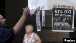 A man looks at newspapers showing the results of yesterday's referendum in central Athens, Greece, July 6, 2015. Greeks overwhelmingly rejected conditions of a rescue package from creditors on Sunday, throwing the future of the country's euro zone members