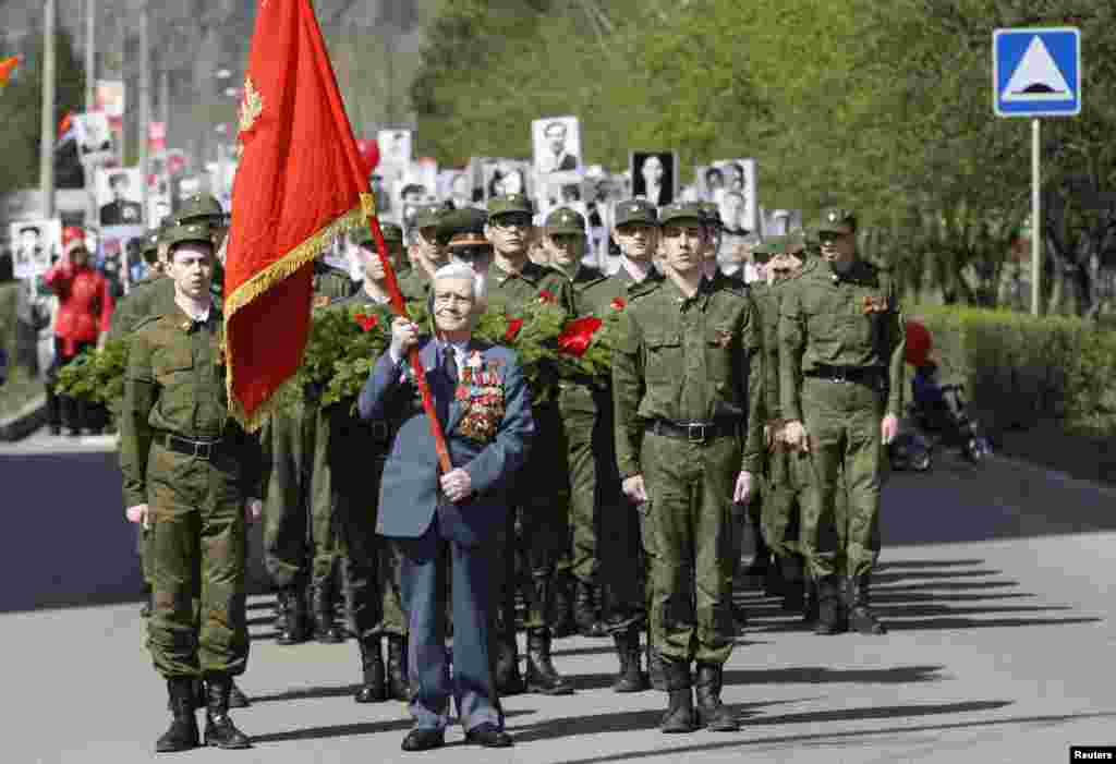 Russian World War II veteran Alexey Samokhin (C), 89, carries a red flag as he leads a procession during the Victory Day celebration in Divnogorsk, near Russia&#39;s Siberian city of Krasnoyarsk.