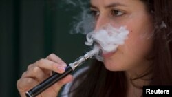 FILE - A woman smokes an electronic cigarette in London, Aug. 19, 2015.