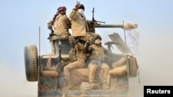 Shi'ite fighters ride on a military vehicle heading toward the airport of Tal Afar during a battle with Islamic State militants in Tal Afar, Iraq, Nov. 16, 2016. 