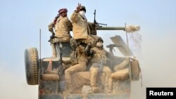 FILE - Shi'ite fighters ride on a military vehicle heading toward the airport of Tal Afar during a battle with Islamic State militants in Tal Afar, Iraq, Nov. 16, 2016. 