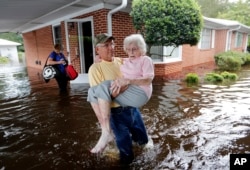 Bob Richling carries Iris Darden, 84, out of her flooded home as her daughter-in-law, Pam Darden, gathers her belongings in the aftermath of Hurricane Florence in Spring Lake, North Carolina, Sept. 17, 2018.
