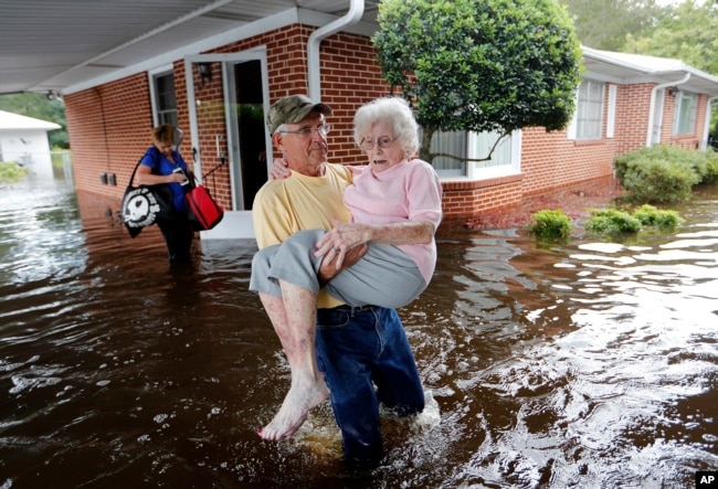 Bob Richling carries Iris Darden, 84, out of her flooded home as her daughter-in-law, Pam Darden, gathers her belongings in the aftermath of Hurricane Florence in Spring Lake, North Carolina, Sept. 17, 2018.