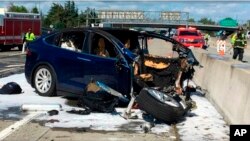 In this March 23, 2018, file photo provided by KTVU, emergency personnel work at the scene where a Tesla electric SUV crashed into a barrier on U.S. Highway 101 in Mountain View, Calif. (KTVU via AP, File)