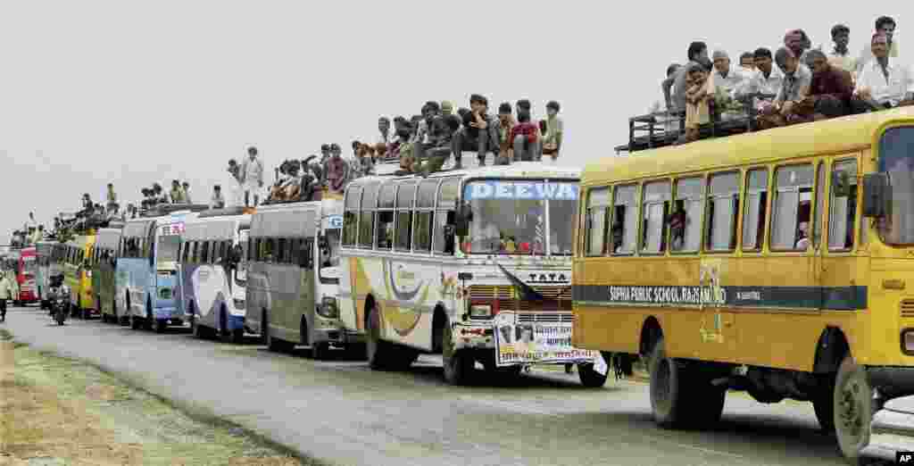 Indian villagers travel on top of buses as they arrive to listen to ruling Congress Party President Sonia Gandhi, unseen, during the foundation stone ceremony of a refinery and petrochemical complex at Pachpadra in Barmer district of Rajasthan state, India, Sept. 22, 2013.