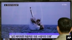 FILE - A South Korean man watches a TV news program showing an image published in North Korea's Rodong Sinmun newspaper of North Korea's ballistic missile believed to have been launched from underwater, at Seoul Railway station in Seoul, South Korea.