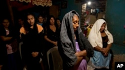 Women pray for Alexander Mora, one of 43 students missing since September, whose bone fragment has now been positively identified among charred remains found near a garbage dump, at the Mora family home in the town of El Pericon, Mexico, Dec. 7, 2014.