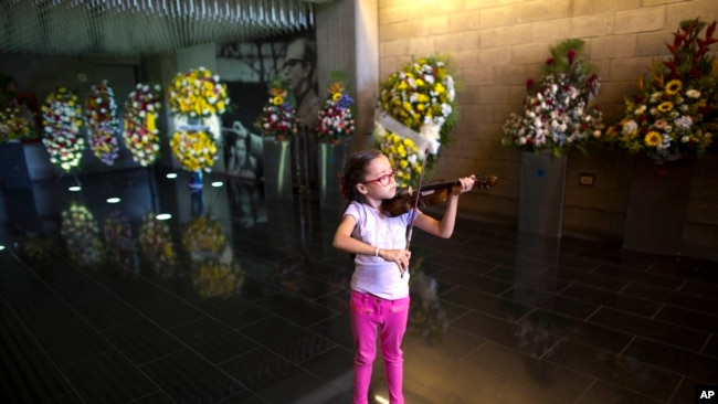 Una niña toca el violín en el auditorio donde se realizaba el velatorio de José Antonio Abreu en Caracas, Venezuela, el domingo, 25 de marzo, de 2018.