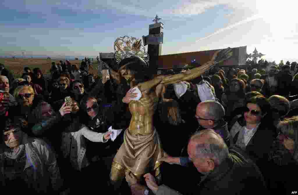 Penitents touch the effigy of "Cristo Salvador" (Christ the Savior) during the Holy Week procession on the beach in Valencia, Spain, April 3, 2015.