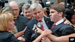 Former Virginia Gov. Bob McDonnell, center, is mobbed by media as he gets into a car with his son, Bobby, right, after he and his wife, Maureen, were convicted on multiple counts of corruption at Federal Court in Richmond, Va., Sept. 4, 2014. 