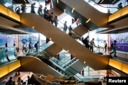 FILE - Tourists descend on an escalator inside a shopping mall at the Peak in Hong Kong, China, Aug. 4, 2017.