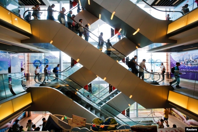 FILE - Tourists descend on an escalator inside a shopping mall at the Peak in Hong Kong, China, Aug. 4, 2017.