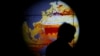 FILE - A woman walks past a map showing the elevation of the sea in the last 22 years during the World Climate Change Conference 2015 (COP21) at Le Bourget, near Paris, France, Dec. 11, 2015. 