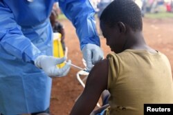 FILE - A Congolese health worker administers Ebola vaccine to a boy who had contact with an Ebola sufferer in the village of Mangina in North Kivu province of the Democratic Republic of the Congo, Aug. 18, 2018.