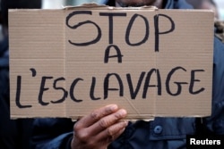 A man holds a placard with the message "Stop Slavery" as he attends a protest against slavery in Libya outside the Lybian Embassy in Paris, Nov. 24, 2017.