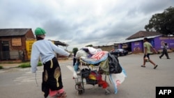 A woman collecting plastic bags carries her cart through the streets of Johannesburg's Alexandra township, December 12, 2012.