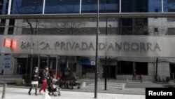 FILE - A couple walk past a Banca Privada d'Andorra (BPA) office in Andorra la Vella, March 29, 2015. 