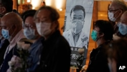 FILE - In this Feb. 7, 2020 file photo, people wearing masks attend a vigil for Chinese doctor Li Wenliang, who was reprimanded for warning about the outbreak of the new coronavirus, in Hong Kong. (AP Photo/Kin Cheung, File)