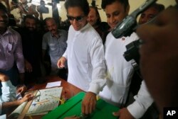 Pakistani politician Imran Khan, center, chief of Pakistan Tehreek-e-Insaf party, casts his vote at a polling station for the parliamentary elections in Islamabad, Pakistan, Wednesday, July 25, 2018.