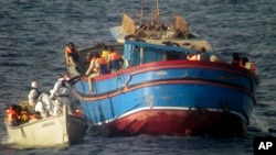 Photo released by the Italian Navy June 30, 2014, shows motor boats from the Italian frigate Grecale approaching a boat overcrowded with migrants in the Mediterranean Sea.