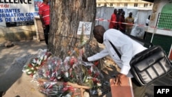 A man lays flowers at a tree on the street of Abidjan where at least 60 persons died in a stampede among crowds gathered for celebratory New Year's Eve fireworks, January 2, 2013.