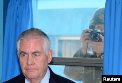 U.S. Secretary of State Rex Tillerson is briefed by U.S. Gen. Vincent K. Brooks, commander of the United Nations Command, Combined Forces Command and United States Forces Korea (not pictured), as a North Korean soldier takes a photograph through a window