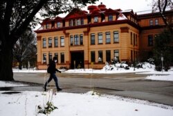 Seorang mahasiswa Universitas Negeri Dakota Utara (NDSU) yang mengenakan masker pelindung berjalan melewati gedung Teknik Selatan di kampus saat wabah COVID-19 berlanjut di Fargo, Dakota Utara, AS, 25 Oktober 2020. (Foto: REUTERS/Bing Guan)