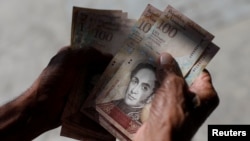 A man counts Venezuelan bolivar notes in downtown Caracas, Venezuela, Jan. 9, 2018.