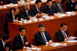 Chinese President Xi Jinping, center, talks to Li Zhanshu, a member of the Politburo Standing Committee, after casting their votes for an amendment to China's constitution that abolishes term limits on the presidency and enable Xi to rule indefinitely.