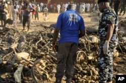 Nigerian police inspect the site of an explosion in Kano, Nigeria, Nov. 28, 2014.