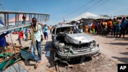Un hombre pasa por un vehículo destrozado después de una explosión en un mercado en la capital, Mogadiscio, Somalia, el 19 de febrero de 2017.