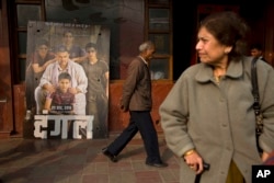 An elderly man walks past a poster of Bollywood movie Dangal, a 2016 Bollywood biopic on an Indian wrestling coach and his two professional wrestler daughters, outside a theater in New Delhi, India.