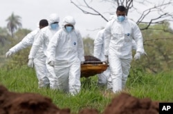 Rescue workers carry away a body they pulled from the mud after a dam collapsed and flooded Brumadinho, Brazil, Jan. 28, 2019.