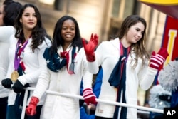 FILE - U.S. gymastics team members, from right, McKayla Maroney, Gabby Douglas and Aly Raisman ride a float in the Macy's Thanksgiving Day Parade in New York, Nov. 22, 2012.