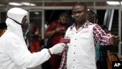 A Nigerian port health official uses a thermometer on a worker at the arrivals hall of Murtala Muhammed International Airport in Lagos, Aug. 6, 2014.