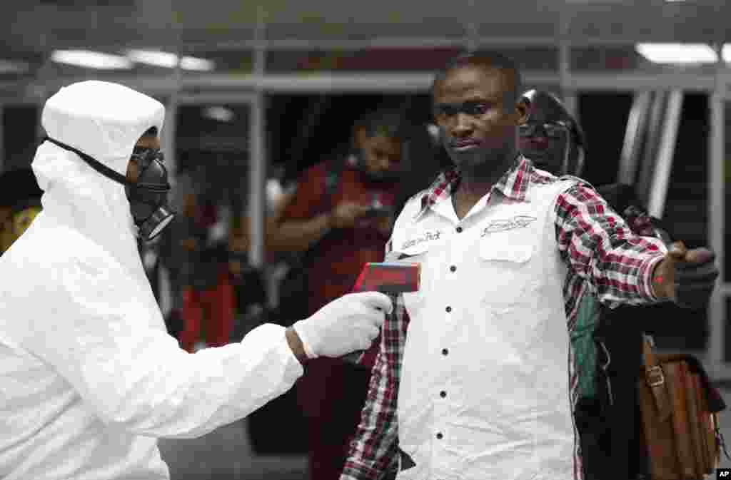 A Nigerian port health official uses a thermometer on a worker at the arrivals hall of Murtala Muhammed International Airport in Lagos, Nigeria, Aug. 6, 2014.