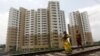 A woman carrying a child walks ahead of her husband on a railway track in front of residential buildings under construction on the outskirts of Kolkata, India, April 26, 2012.